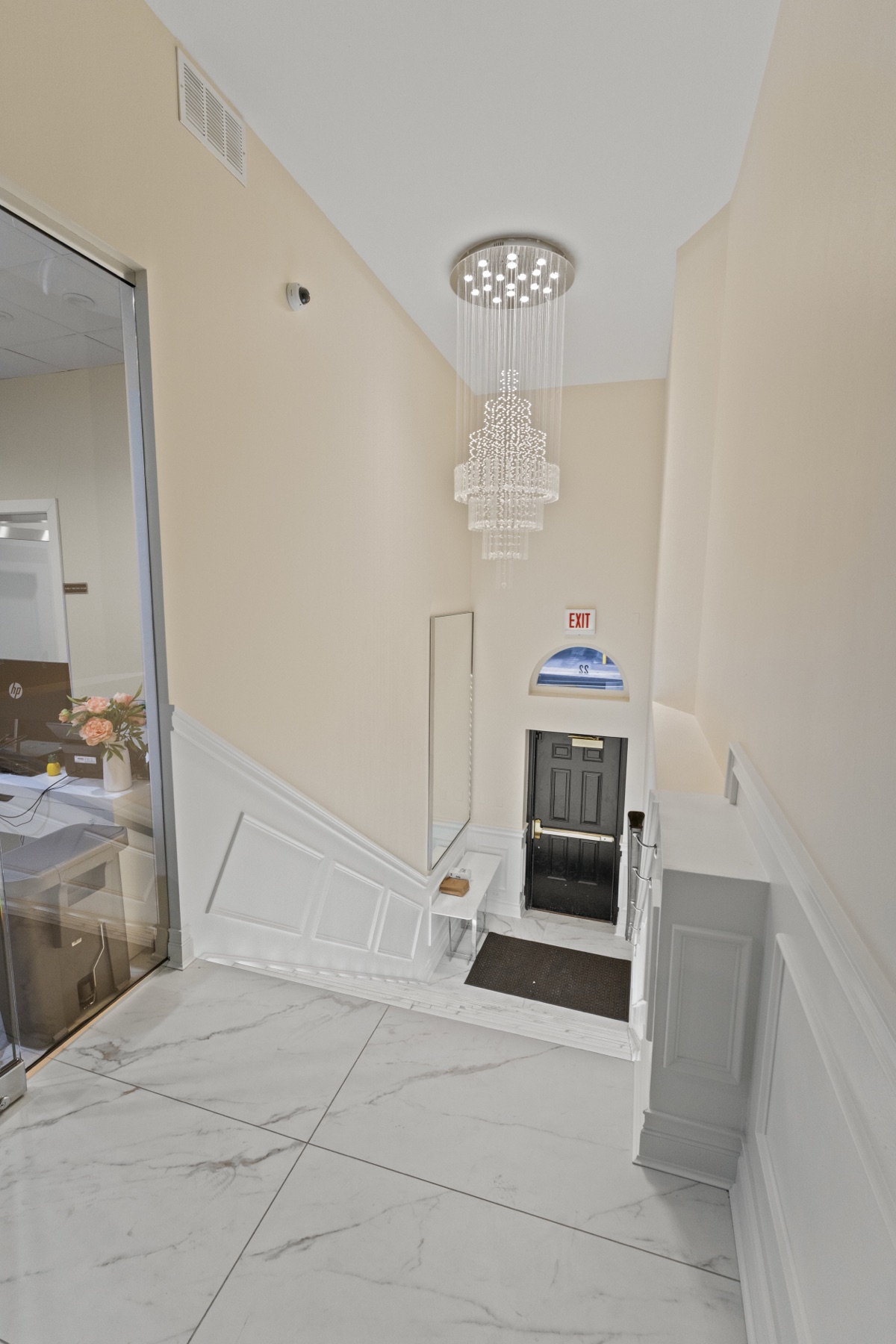 The building's main entry corridor: marble floors, white wainscoting and a crystal chandelier.