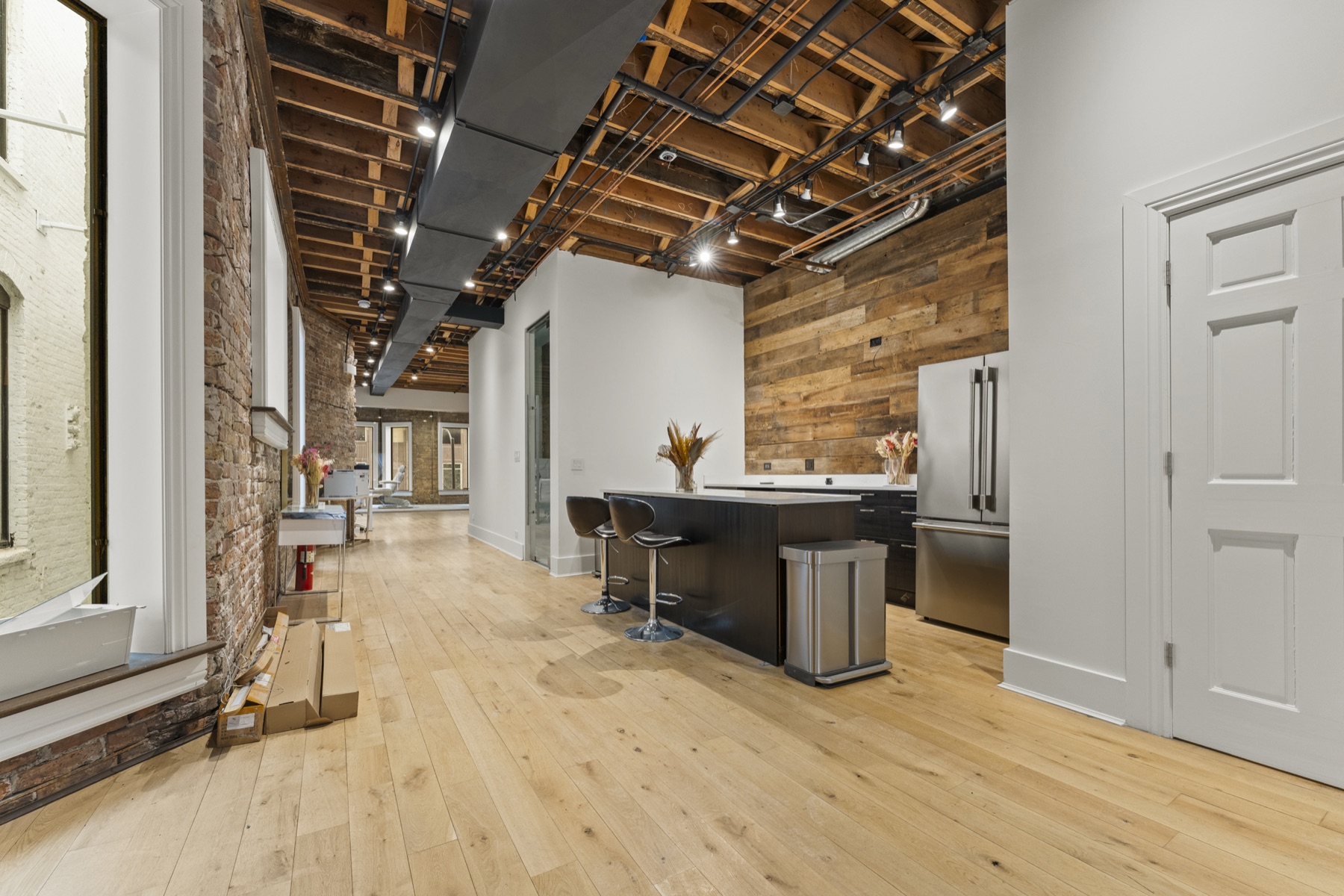 Shared kitchenette with reclaimed wood feature wall and exposed wood-beam ceiling.