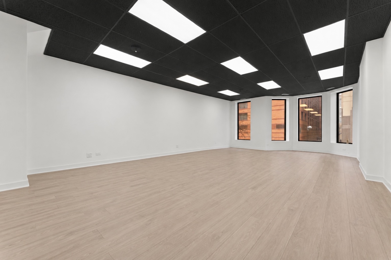 Loft B — the largest single room: open white walls, bay windows facing the River North brick, and wide-plank wood floors.