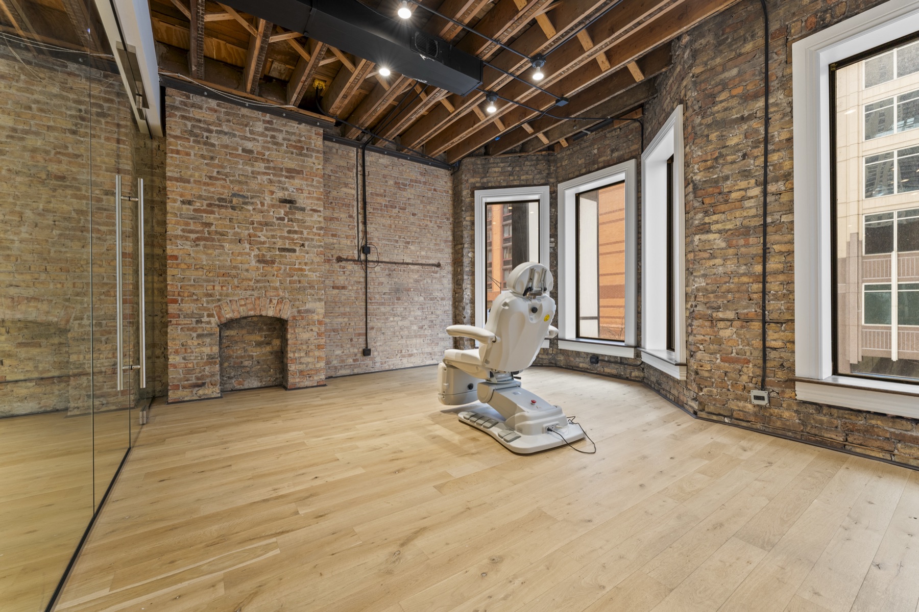 Suite interior detail — alcove with reclaimed brick fireplace, original windows, light wood floor.