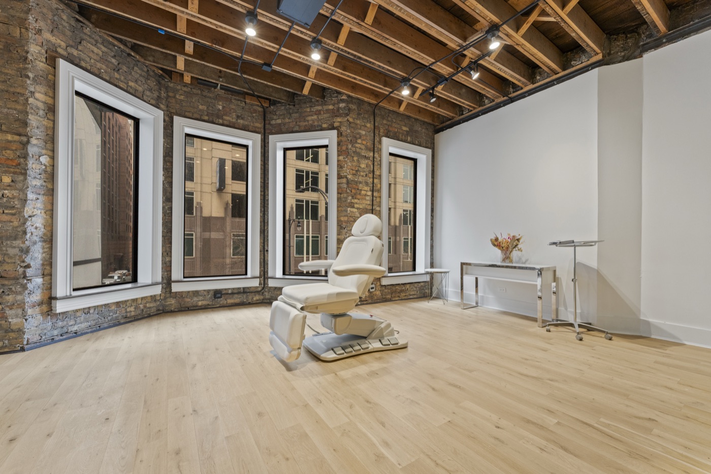 Suite A — treatment chair against three industrial bay windows with exposed brick walls.