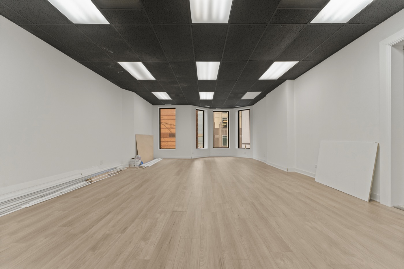 Suite B — open layout with bay windows and laminate flooring, ready for buildout.
